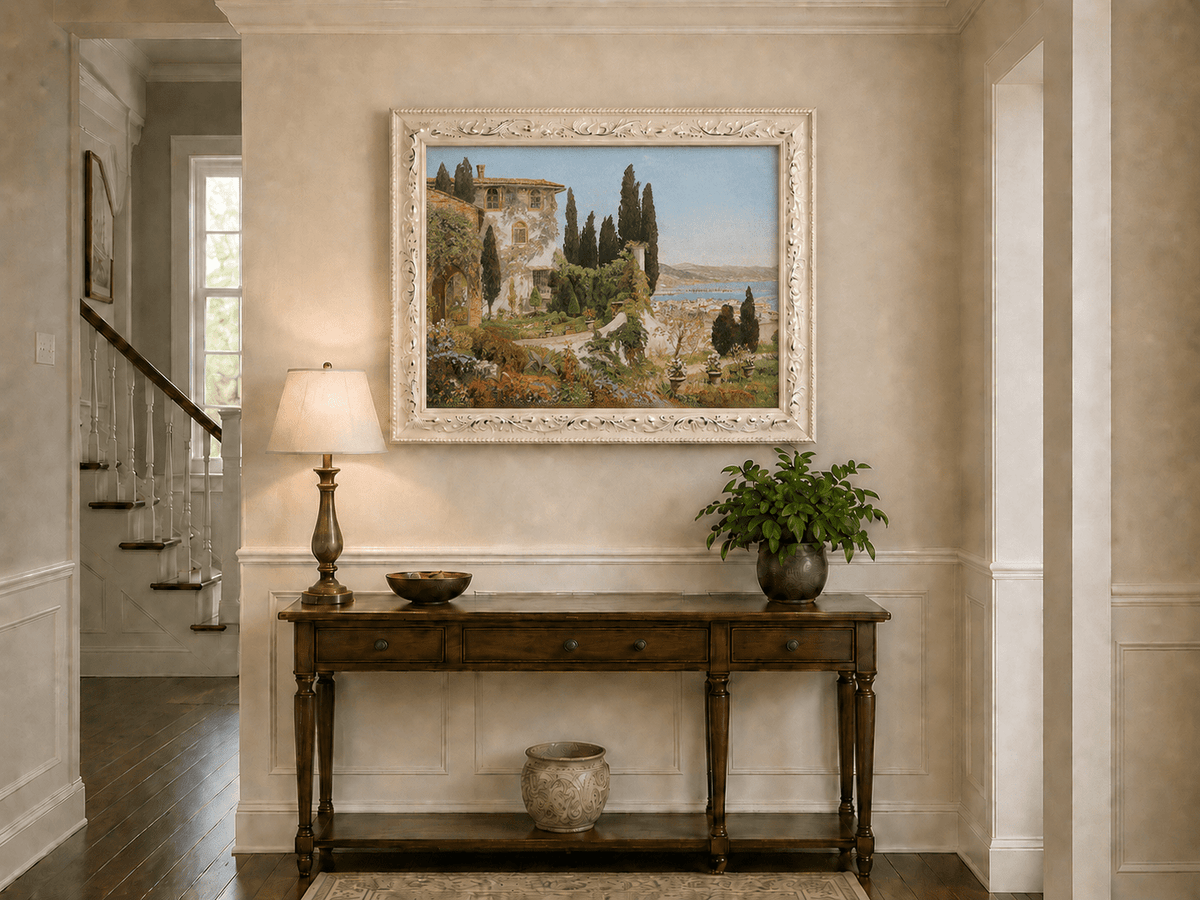 Framed hand-painted Italian garden oil painting with cypress trees overlooking the sea displayed above an entryway console table.