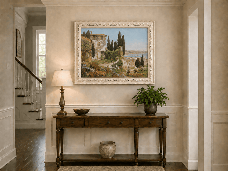 Framed hand-painted Italian garden oil painting with cypress trees overlooking the sea displayed above an entryway console table.
