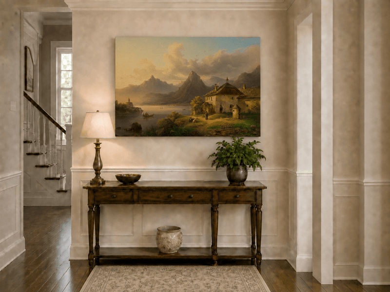 Hand-painted alpine lake cottage with sunset mountain landscape oil painting displayed above a console table in a hallway interior.