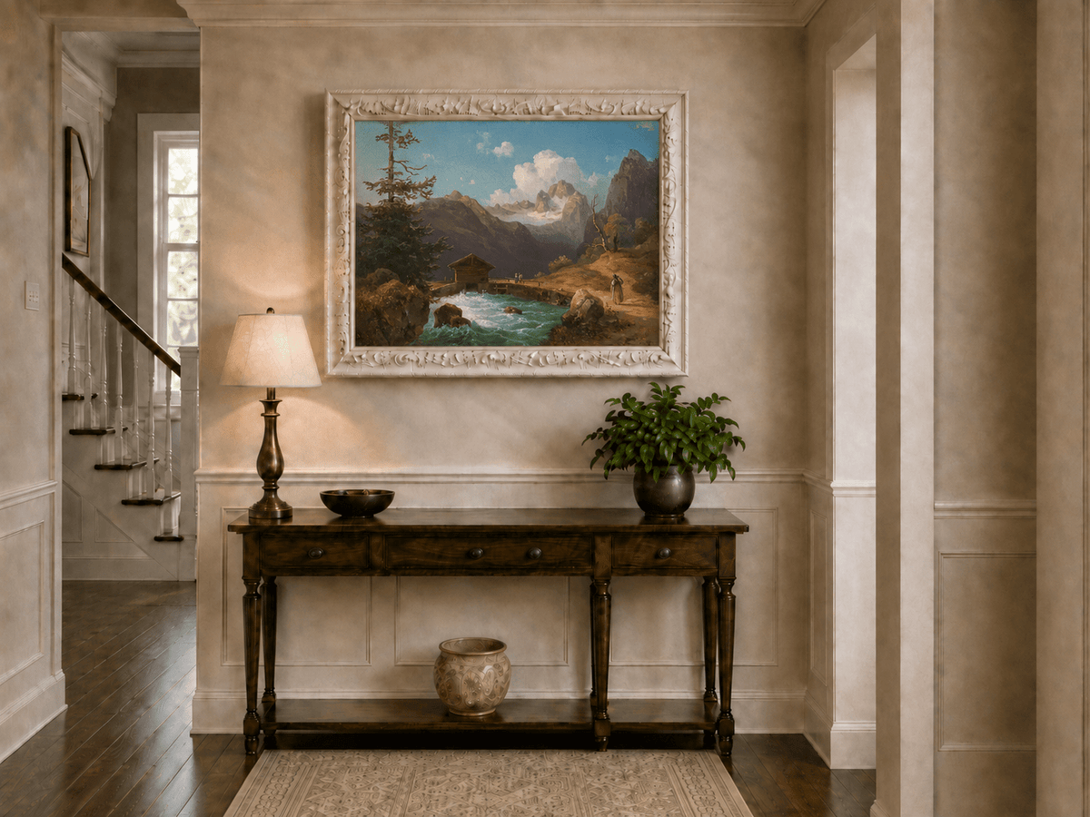 Hand-painted alpine river cabin and mountain valley landscape oil painting displayed above a console table in a hallway interior.