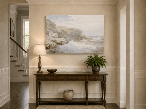 Unframed hand-painted coastal cliffs oil painting with waves breaking along the rocky shore displayed above an entryway console table.