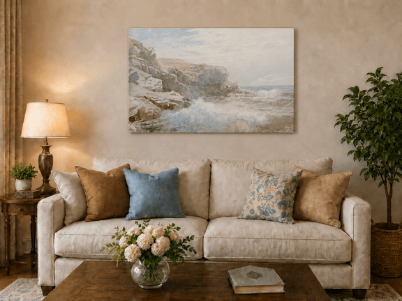 Unframed hand-painted coastal cliffs oil painting with waves crashing against pale rocks displayed above a neutral living room sofa.