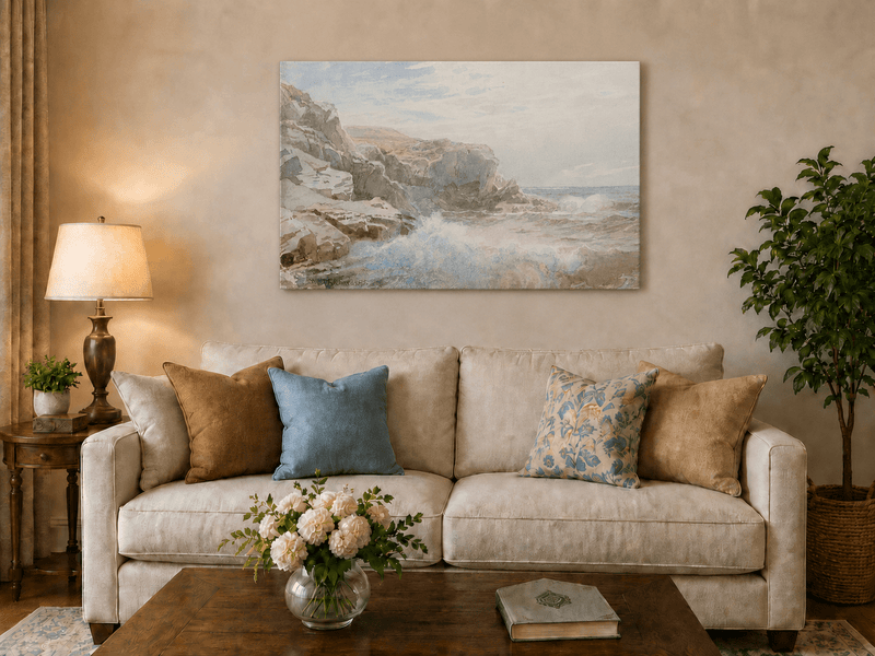 Unframed hand-painted coastal cliffs oil painting with waves crashing against pale rocks displayed above a neutral living room sofa.