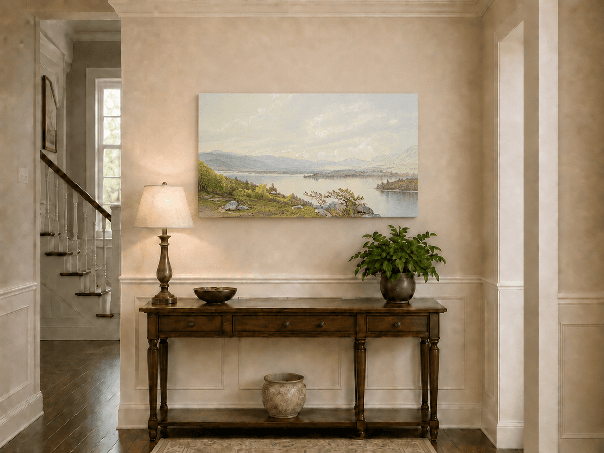 Unframed hand-painted expansive lake oil painting with distant mountains, trees and calm water displayed above an entryway console table.