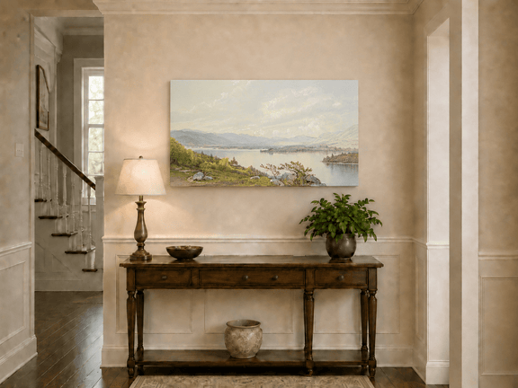 Unframed hand-painted expansive lake oil painting with distant mountains, trees and calm water displayed above an entryway console table.