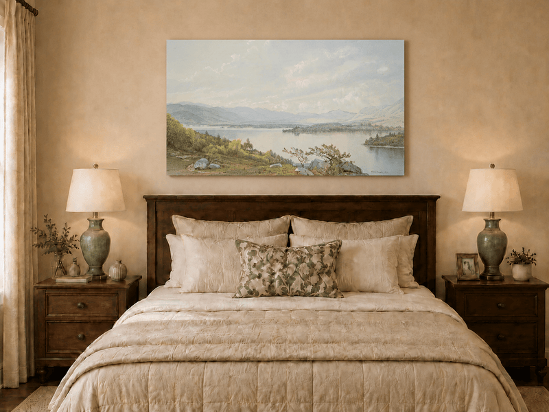 Unframed hand-painted expansive lake oil painting with distant mountains, trees and calm water displayed above a wooden bed in a neutral bedroom.