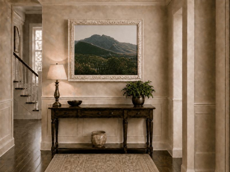 Hand-painted mountain view with bridge and greenery landscape oil painting displayed above a console table in a hallway interior.
