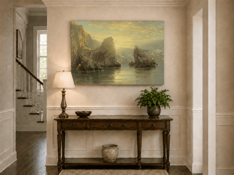 Unframed hand-painted seascape oil painting with rock cliffs, calm water and glowing skies displayed above an entryway console table.