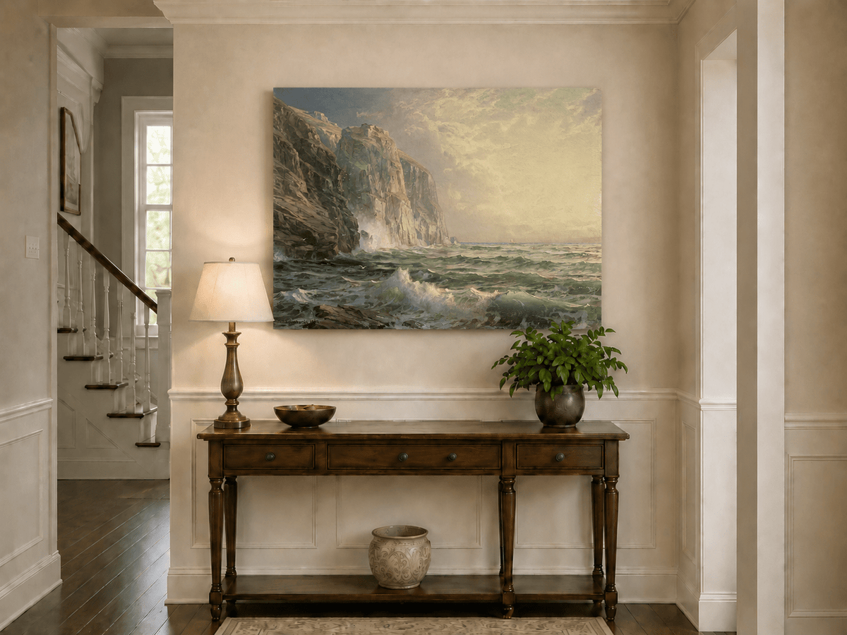 Unframed hand-painted coastal oil painting with tall cliffs, rolling waves and glowing skies displayed above an entryway console table.