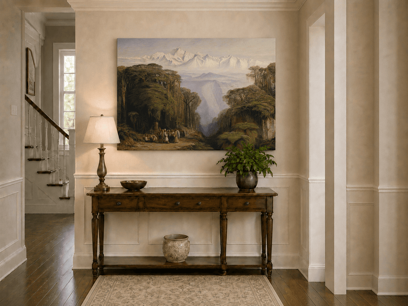 Hand-painted tropical jungle with snow-capped peaks and villagers landscape oil painting displayed above a console table in a hallway interior.
