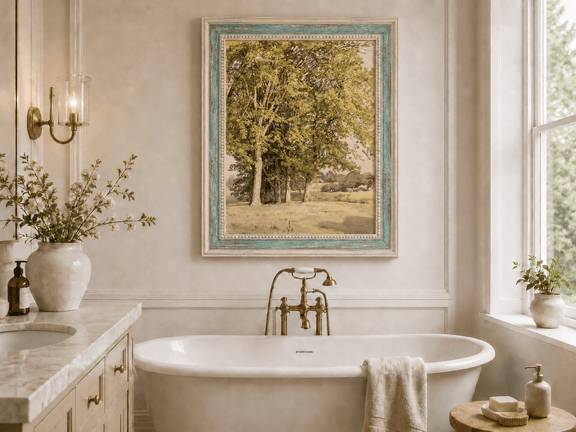Framed hand-painted rural landscape oil painting with leafy trees and a grassy field displayed above a freestanding bathtub.