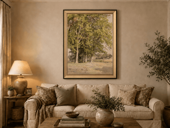 Framed hand-painted rural landscape oil painting with leafy trees and a grassy field displayed above a neutral living room sofa.