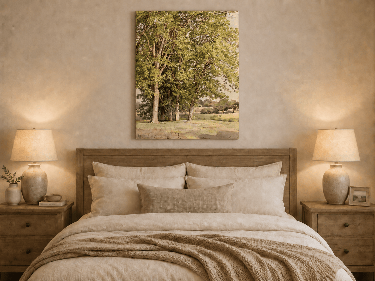 Unframed hand-painted rural landscape oil painting with leafy trees and a grassy field displayed above a wooden bed in a neutral bedroom.