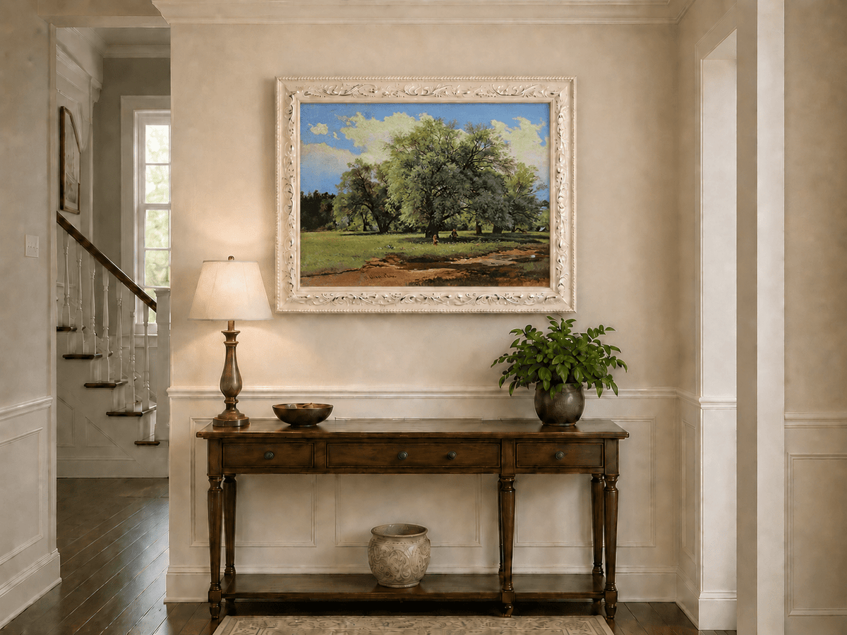 Framed hand-painted meadow oil painting with trees and small figures displayed above an entryway console table.