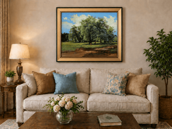 Framed hand-painted meadow oil painting with trees and small figures displayed above a neutral living room sofa.