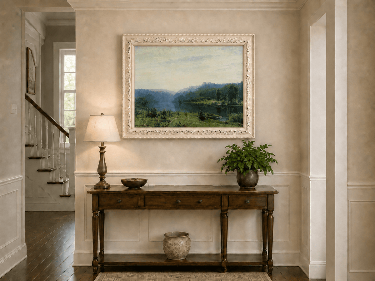 Framed hand-painted misty lake oil painting with a forested shore and distant hills displayed above an entryway console table.