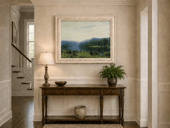 Framed hand-painted misty lake oil painting with a forested shore and distant hills displayed above an entryway console table.