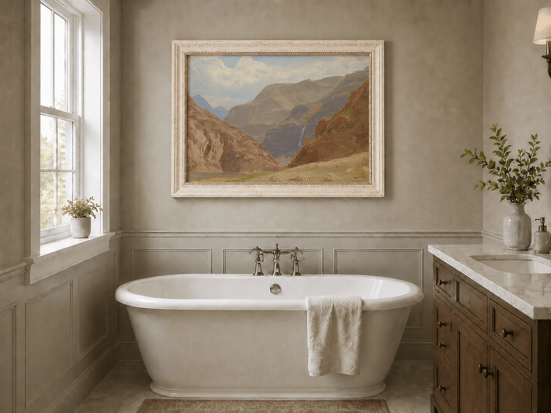 Framed hand-painted mountain canyon oil painting with a waterfall and grassy valley floor displayed above a freestanding bathtub.