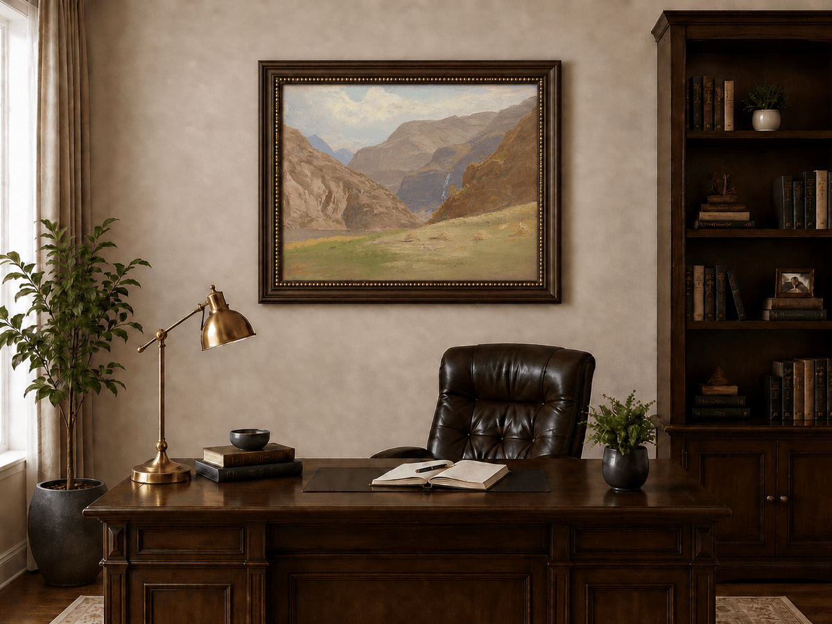 Framed hand-painted mountain canyon oil painting with a waterfall and grassy valley floor displayed above a traditional home office desk.
