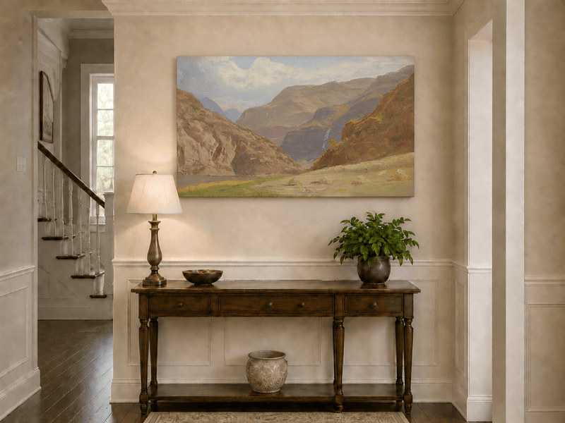 Unframed hand-painted mountain canyon oil painting with a waterfall and grassy valley floor displayed above an entryway console table.