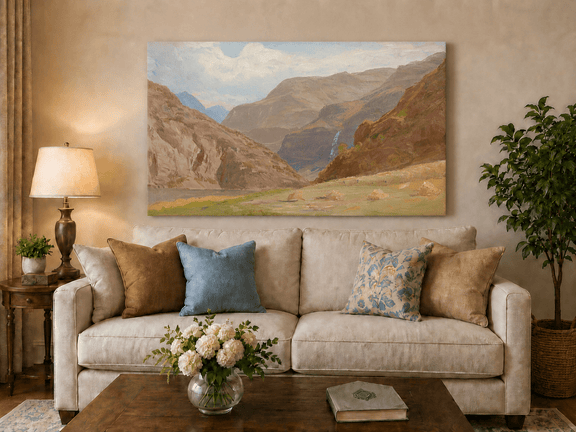 Unframed hand-painted mountain canyon oil painting with a waterfall and grassy valley floor displayed above a neutral living room sofa.