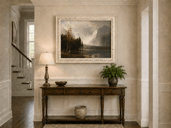 Framed hand-painted mountain lake oil painting with a deer herd and autumn trees displayed above an entryway console table.