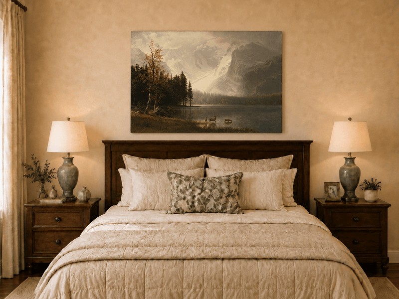 Unframed hand-painted mountain lake oil painting with a deer herd and autumn trees displayed above a wooden bed in a neutral bedroom.