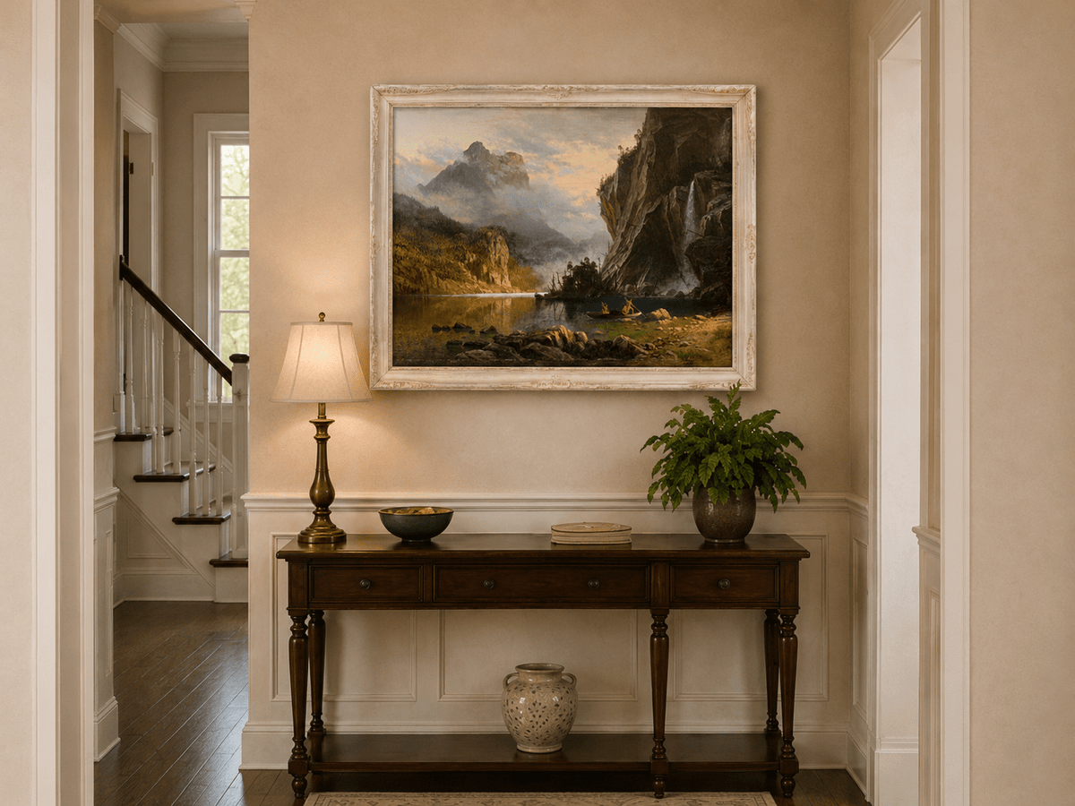 Framed hand-painted mountain lake oil painting with Native American figures in a canoe above an entryway console table.