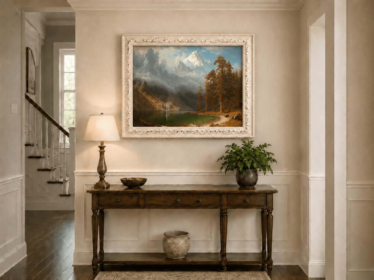 Framed hand-painted mountain lake oil painting with redwood trees and a bear displayed above an entryway console table.