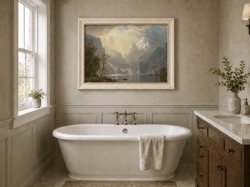 Framed hand-painted mountain lake oil painting with misty peaks in soft light displayed above a freestanding bathtub.