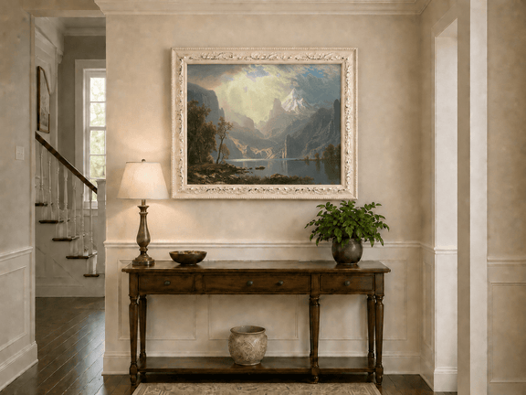 Framed hand-painted mountain lake oil painting with misty peaks in soft light displayed above an entryway console table.