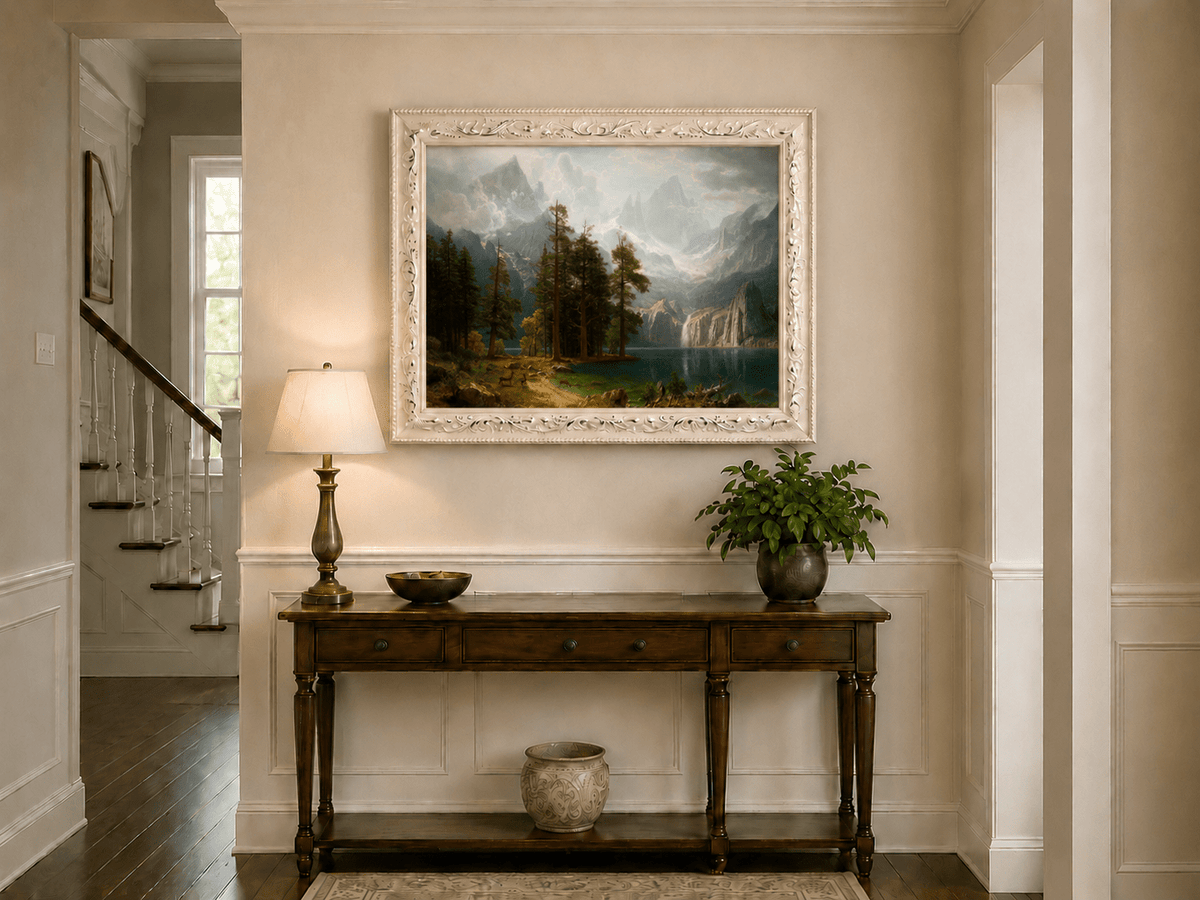 Framed hand-painted mountain lake oil painting with pine forest, waterfall and misty peaks displayed above an entryway console table.