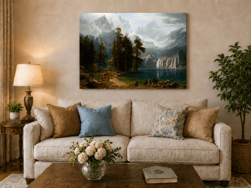 Unframed hand-painted mountain lake oil painting with pine forest, waterfall and misty peaks displayed above a neutral living room sofa.