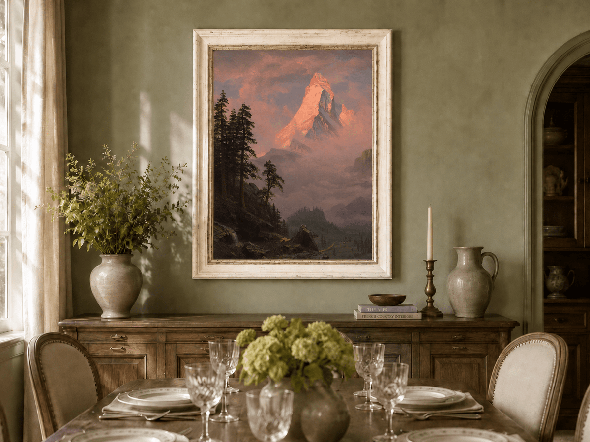 Framed hand-painted mountain oil painting with a sunlit peak, dark forest and mist displayed above a formal dining table.