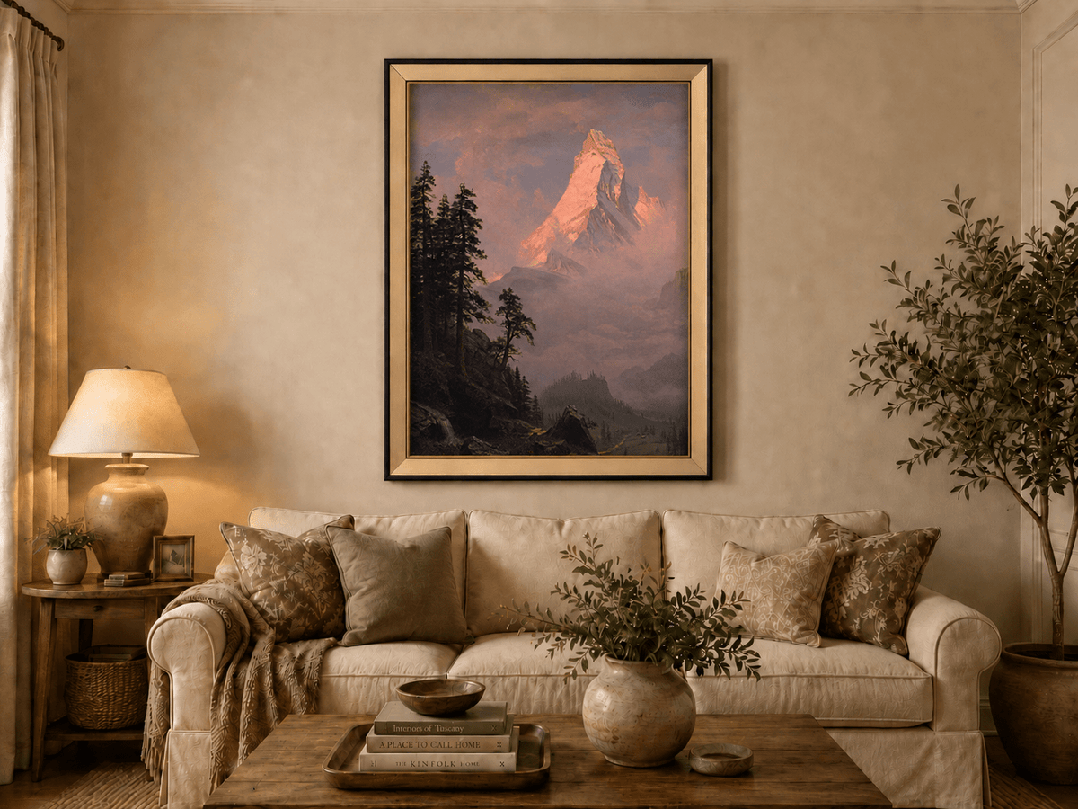 Framed hand-painted mountain oil painting with a sunlit peak, dark forest and mist displayed above a neutral living room sofa.