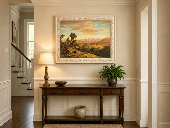 Framed hand-painted mountain valley panorama with golden hills and distant peaks displayed above an entryway console table.