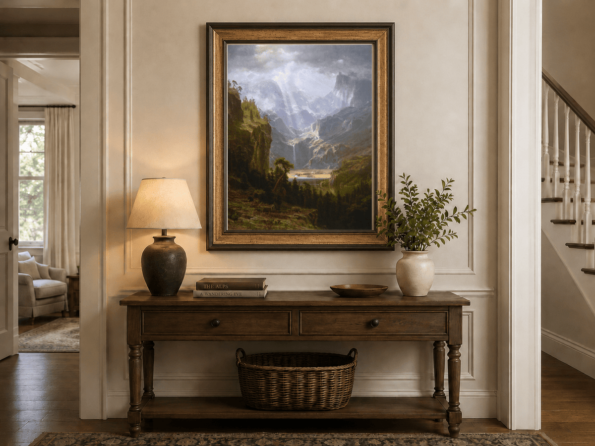 Framed hand-painted mountain valley oil painting with a waterfall and lake displayed above an entryway console table.