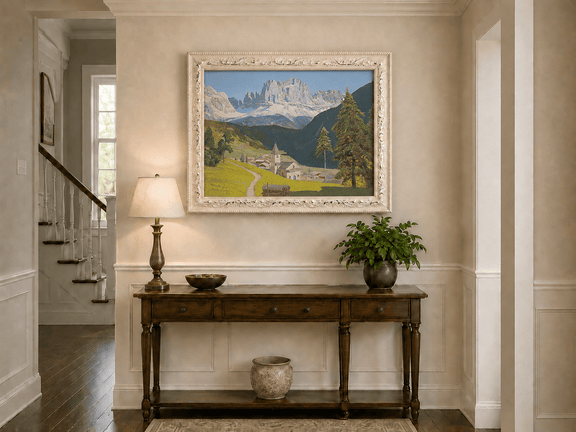 Framed hand-painted alpine landscape oil painting with a mountain village, church and path displayed above an entryway console table.