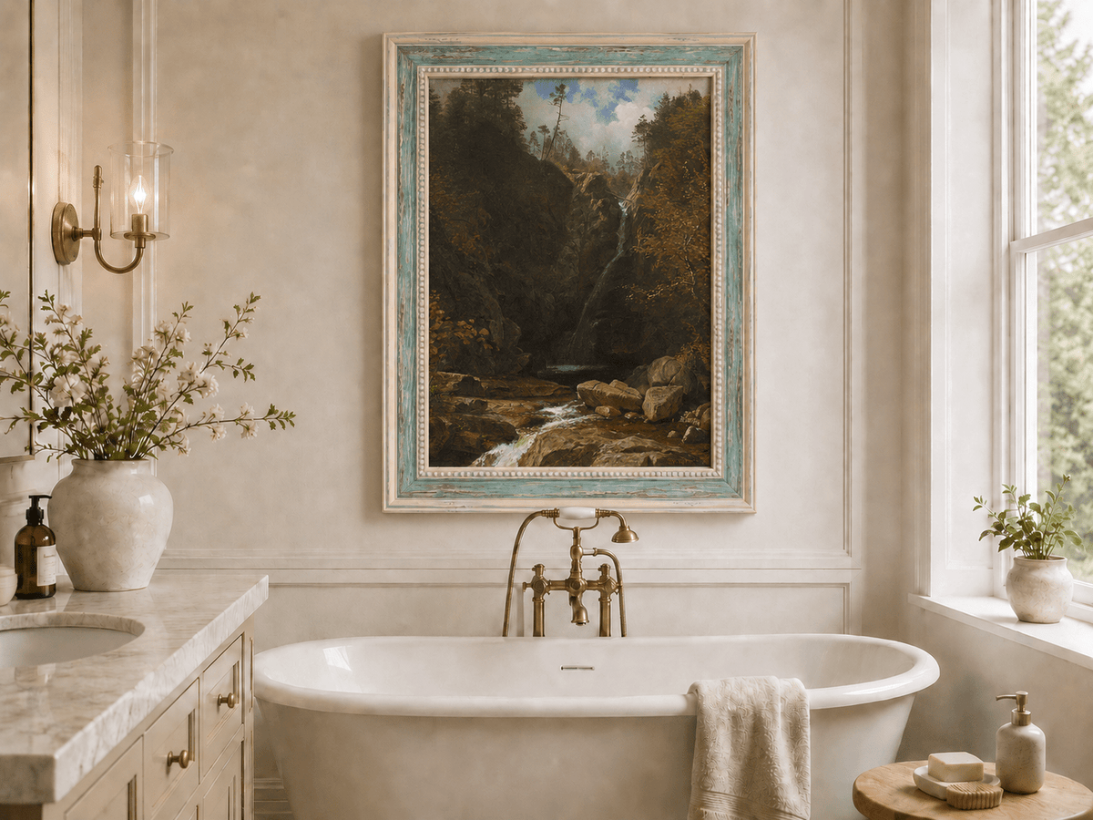Framed hand-painted mountain waterfall oil painting through a dark autumn forest displayed above a freestanding bathtub.