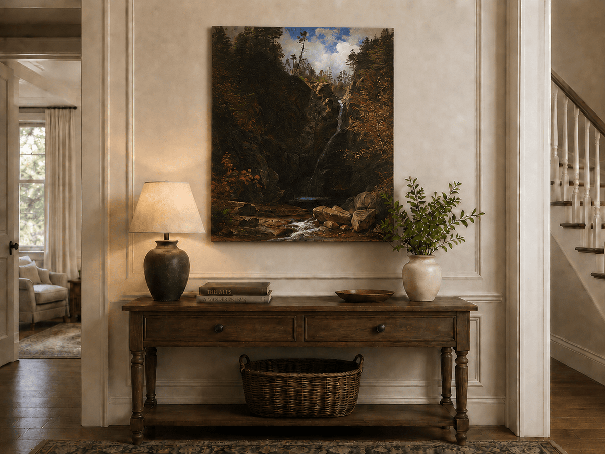 Unframed hand-painted mountain waterfall oil painting through a dark autumn forest displayed above an entryway console table.