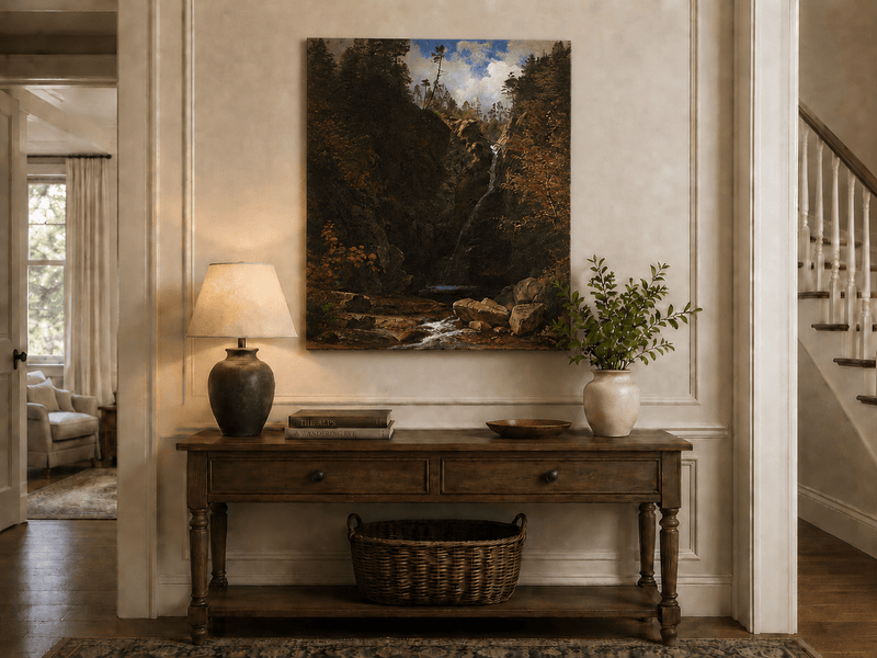Unframed hand-painted mountain waterfall oil painting through a dark autumn forest displayed above an entryway console table.