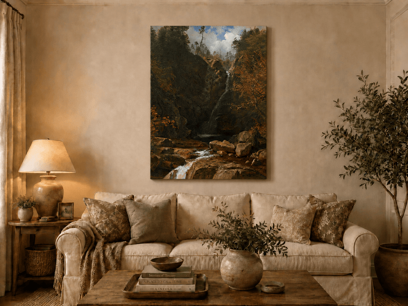 Unframed hand-painted mountain waterfall oil painting through a dark autumn forest displayed above a neutral living room sofa.