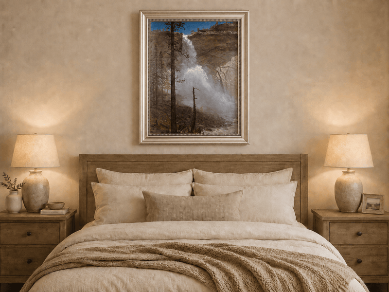 Framed hand-painted mountain waterfall oil painting with rocky cliffs and pine forest displayed above a wooden bed in a neutral bedroom.