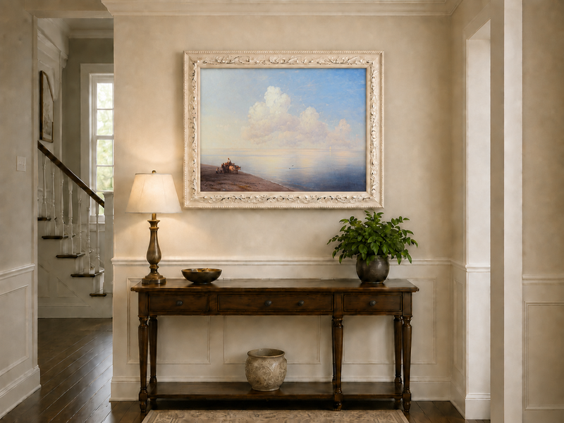 Hand-painted quiet seaside shore with ox cart landscape oil painting displayed above a console table in a hallway interior.