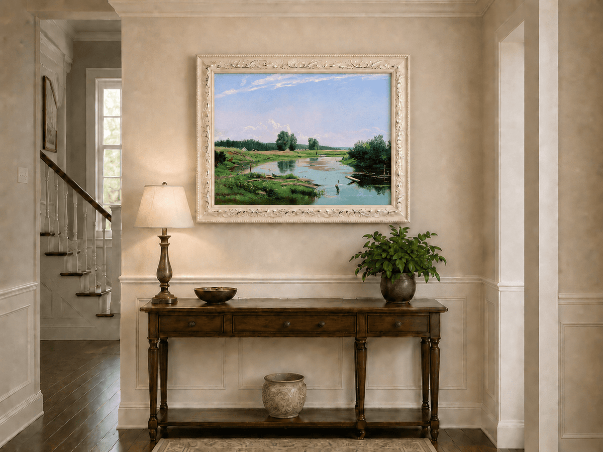Framed hand-painted countryside oil painting with a winding river, green fields and trees displayed above an entryway console table.
