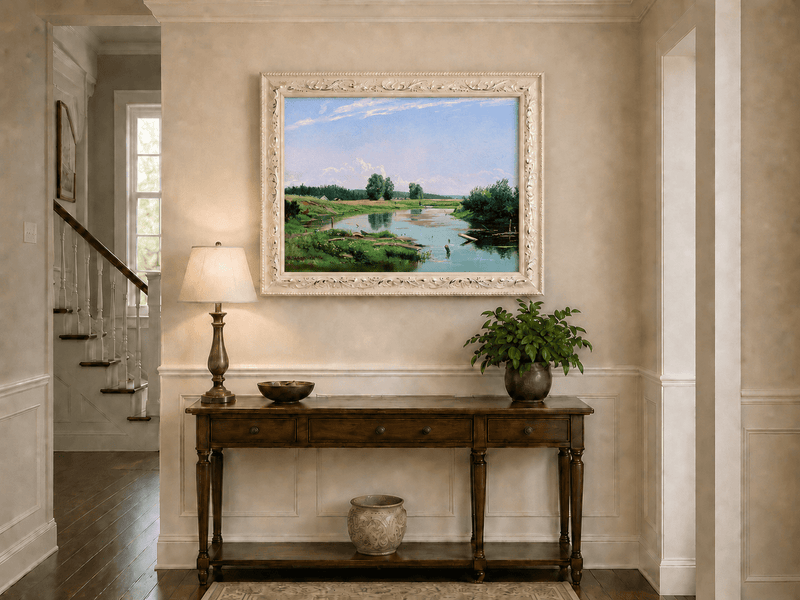 Framed hand-painted countryside oil painting with a winding river, green fields and trees displayed above an entryway console table.