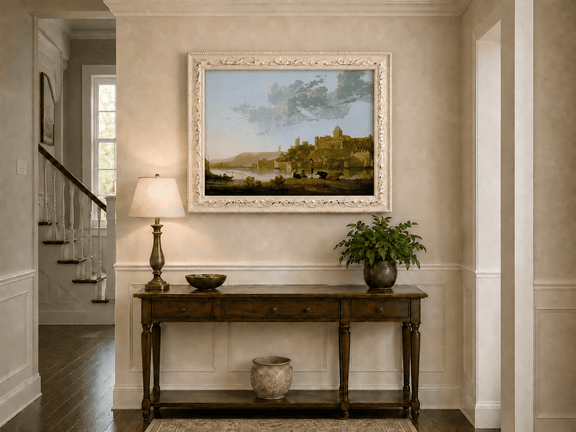 Framed hand-painted riverside castle town oil painting with fishermen at sunset displayed above an entryway console table.