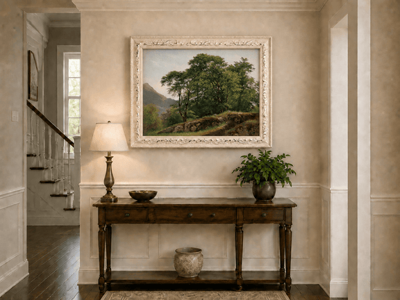 Framed hand-painted landscape oil painting with a rocky hillside, oak tree and distant mountains displayed above an entryway console table.