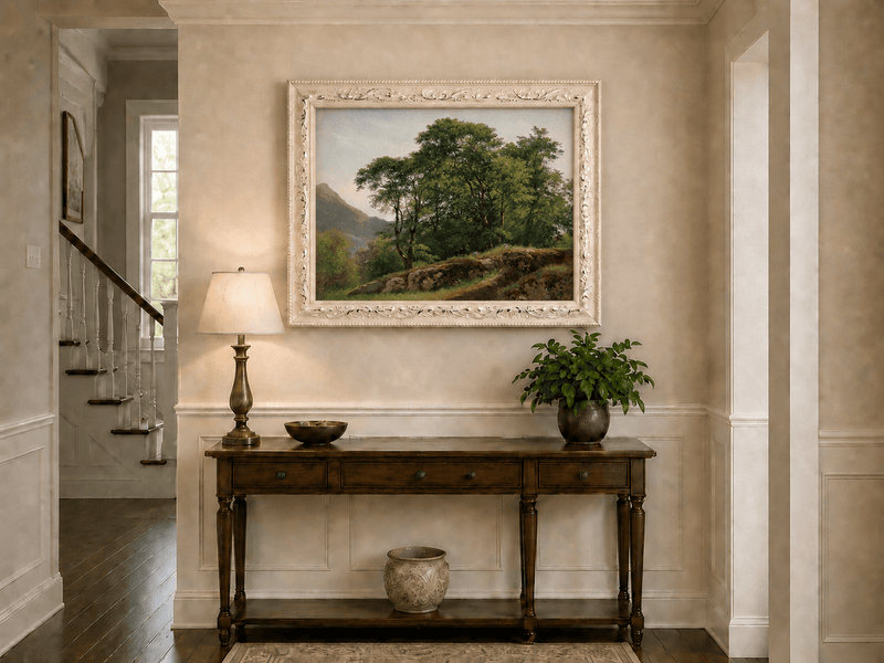 Framed hand-painted landscape oil painting with a rocky hillside, oak tree and distant mountains displayed above an entryway console table.