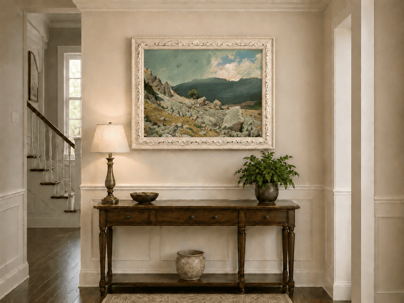 Framed hand-painted alpine oil painting with a rocky slope and distant mountain peaks displayed above an entryway console table.